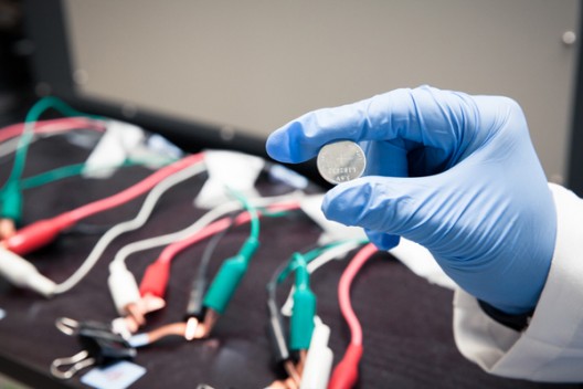 This prototype lithium ion battery contains a silicon electrode protected with a coating of self-healing polymer. The cables and clips in the background are part of an apparatus for testing the battery's performance. Photo: Brad Plummer / SLAC